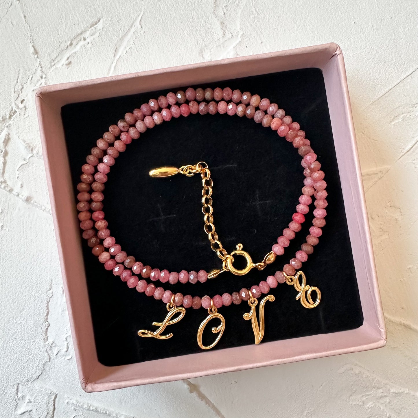 POWER OF LOVE NECKLACE close-up showing rhodochrosite stones and LOVE letter details.